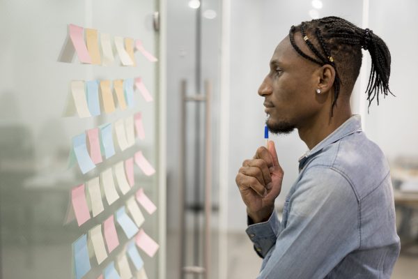 side-view-man-thinking-office-while-looking-sticky-notes